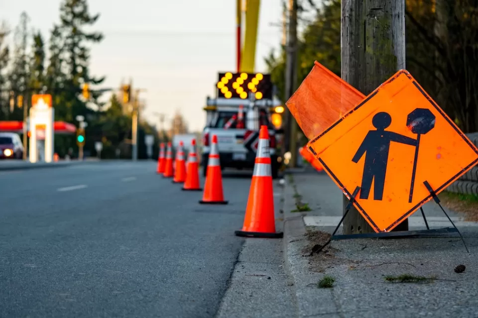 Orange sign and traffic cones indicating work zone on road.